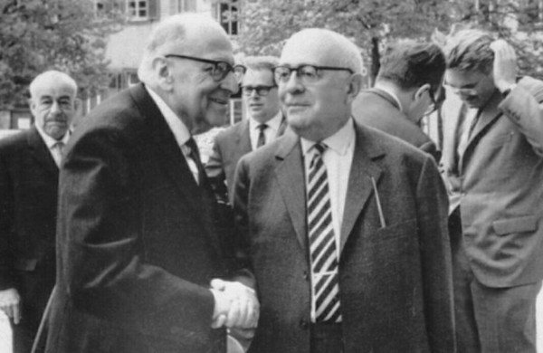 1964년 독일 하이델베르크에서 악수를 나누고 있는 막스 호르크하이머(왼편)와 테오도어 아도르노. 뒤편 오른쪽에 머리를 쓸어 넘기고 있는 사람이 위르겐 하버마스. 사진: 위키미디어 코먼스 <br>